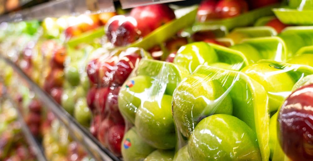 In Folie verpackte Aepfel, rot und gruen in einem Supermarktregal