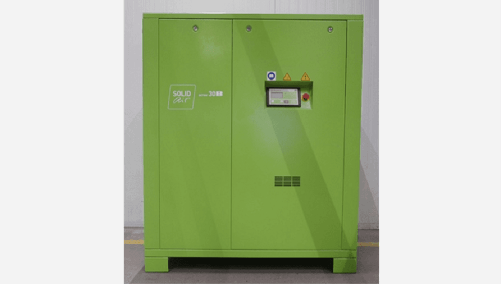 Green industrial air compressor with control panel, labeled "SOLID Air," standing in a warehouse setting.