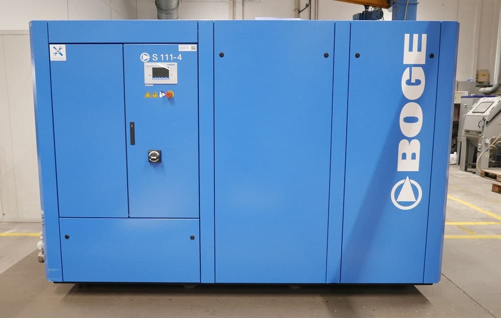 Blue BOGE air compressor unit in an industrial setting, featuring control panel and safety labels.