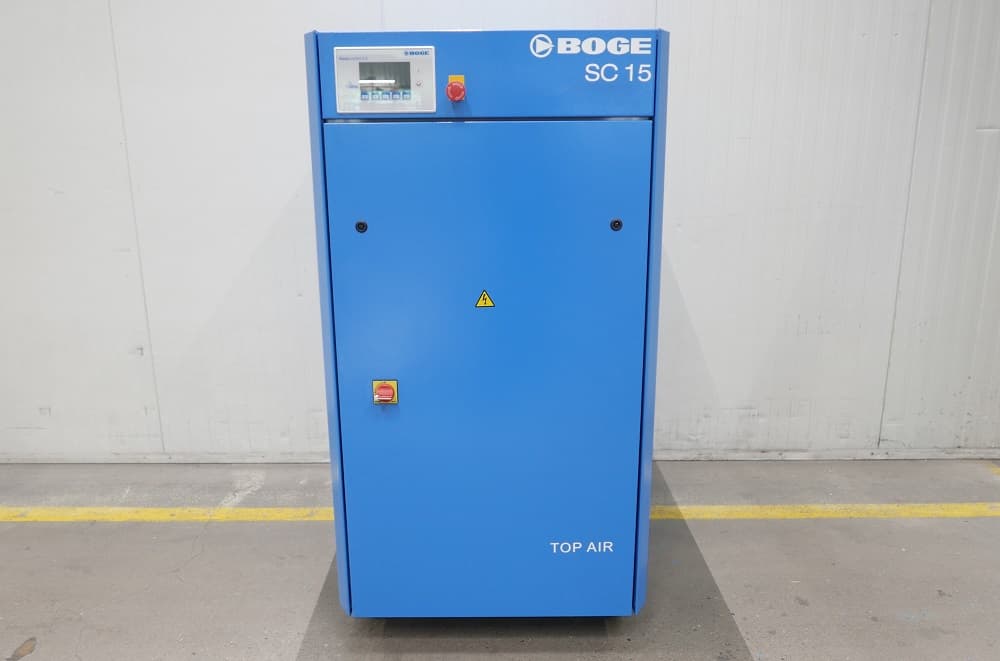 Blue BOGE SC 15 air compressor unit with control panel, emergency stop button, and safety warning symbol, standing in an industrial setting.