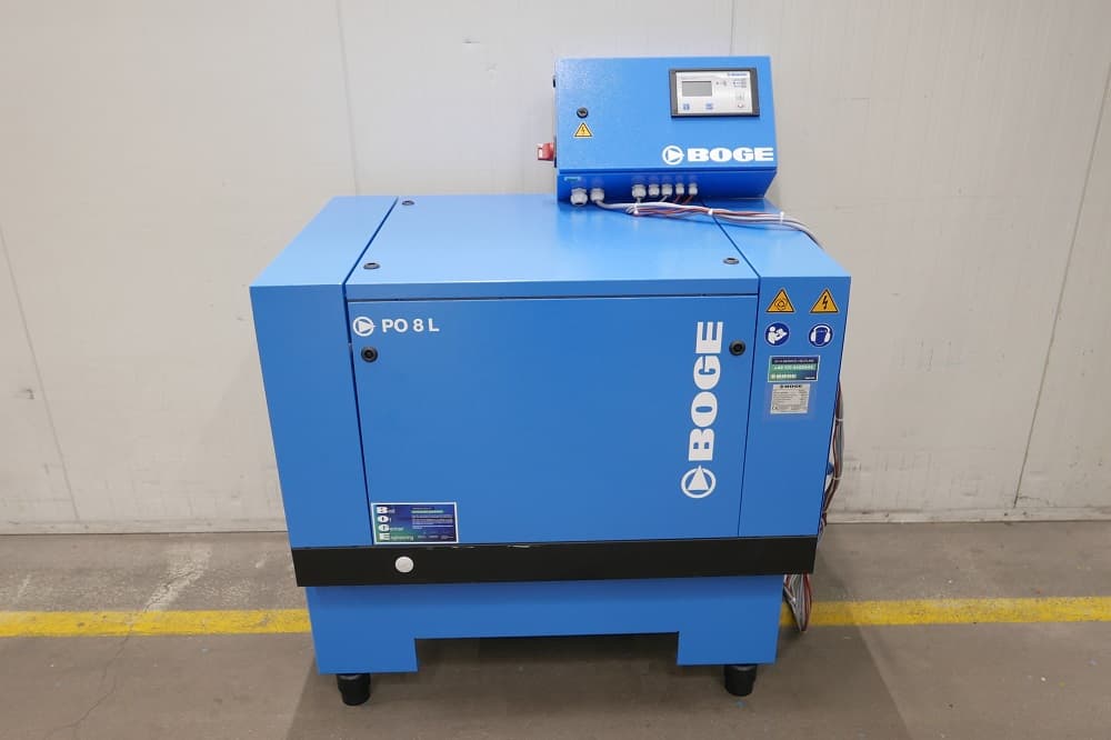 Blue BOGE air compressor with control panel, placed on a concrete floor against a white wall.