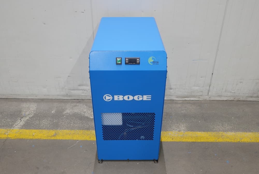 BOGE refrigerant dryer in blue, standing on a concrete floor with a yellow line, featuring control panel and ventilation grille.