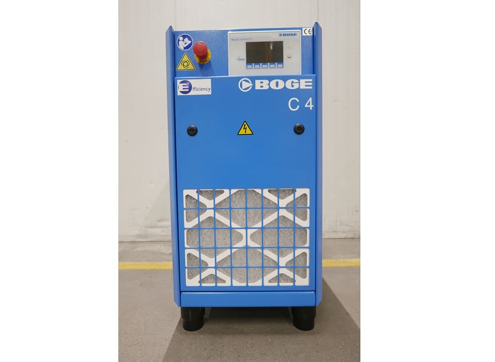 BOGE C4 air compressor in blue, featuring a control panel and safety labels, standing on a concrete floor.
