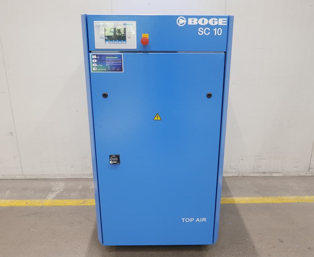 Blue BOGE SC 10 air compressor with control panel and safety warning symbol, standing on a concrete floor.