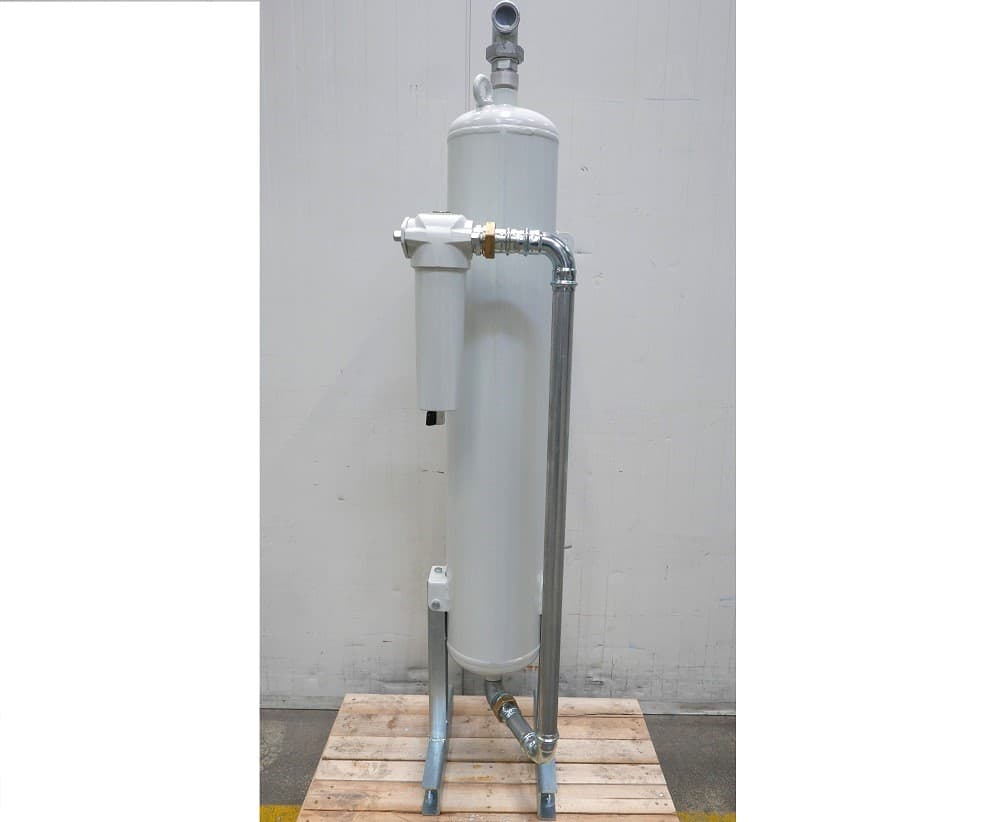 Industrial air filter system with white cylindrical body and metal piping, mounted on a wooden pallet.