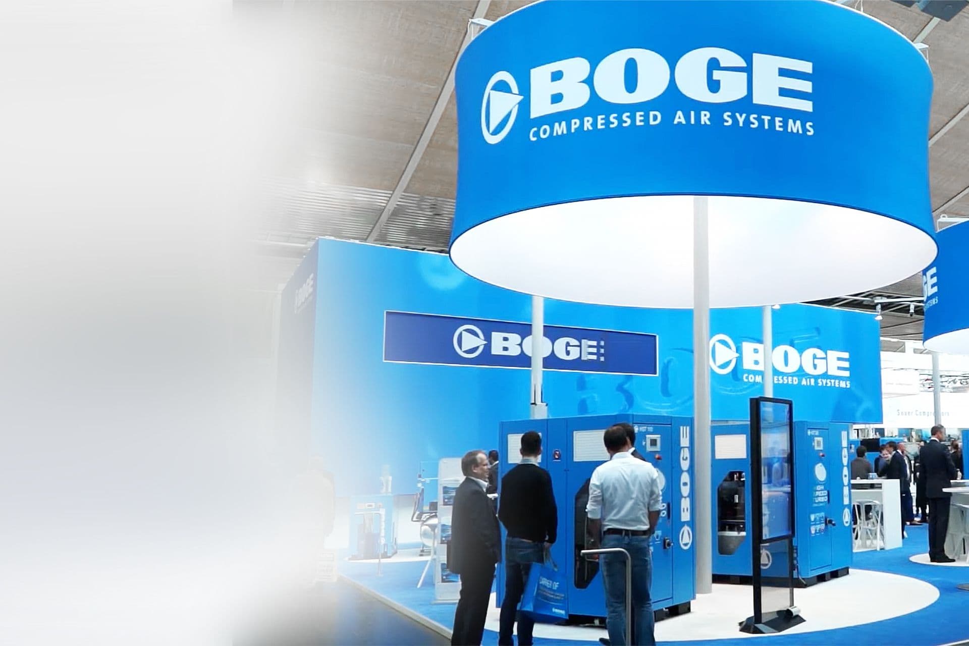 Blauer Messestand von BOGE mit Kompressoren, großen Logos und Personen im Vordergrund
