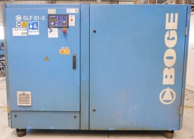 Blue BOGE SLF 51-3 air compressor with control panel, safety labels, and logo in a workshop setting.