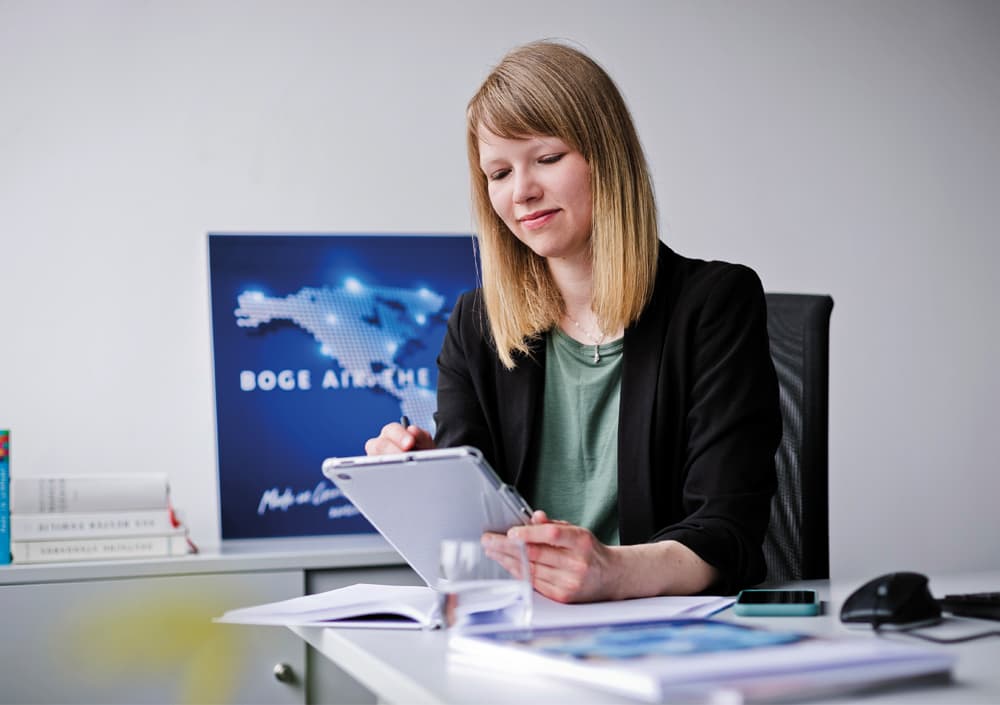 BOGE Mitarbeiterin sitzt am Schreibtisch mit einem Tablet in der Hand