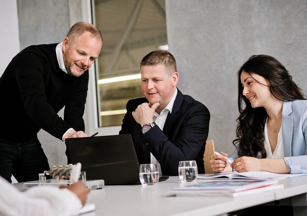 Drei BOGE Mitarbeiter sitzen in einem Konferenzraum und schauen gemeinsam auf einen Laptop