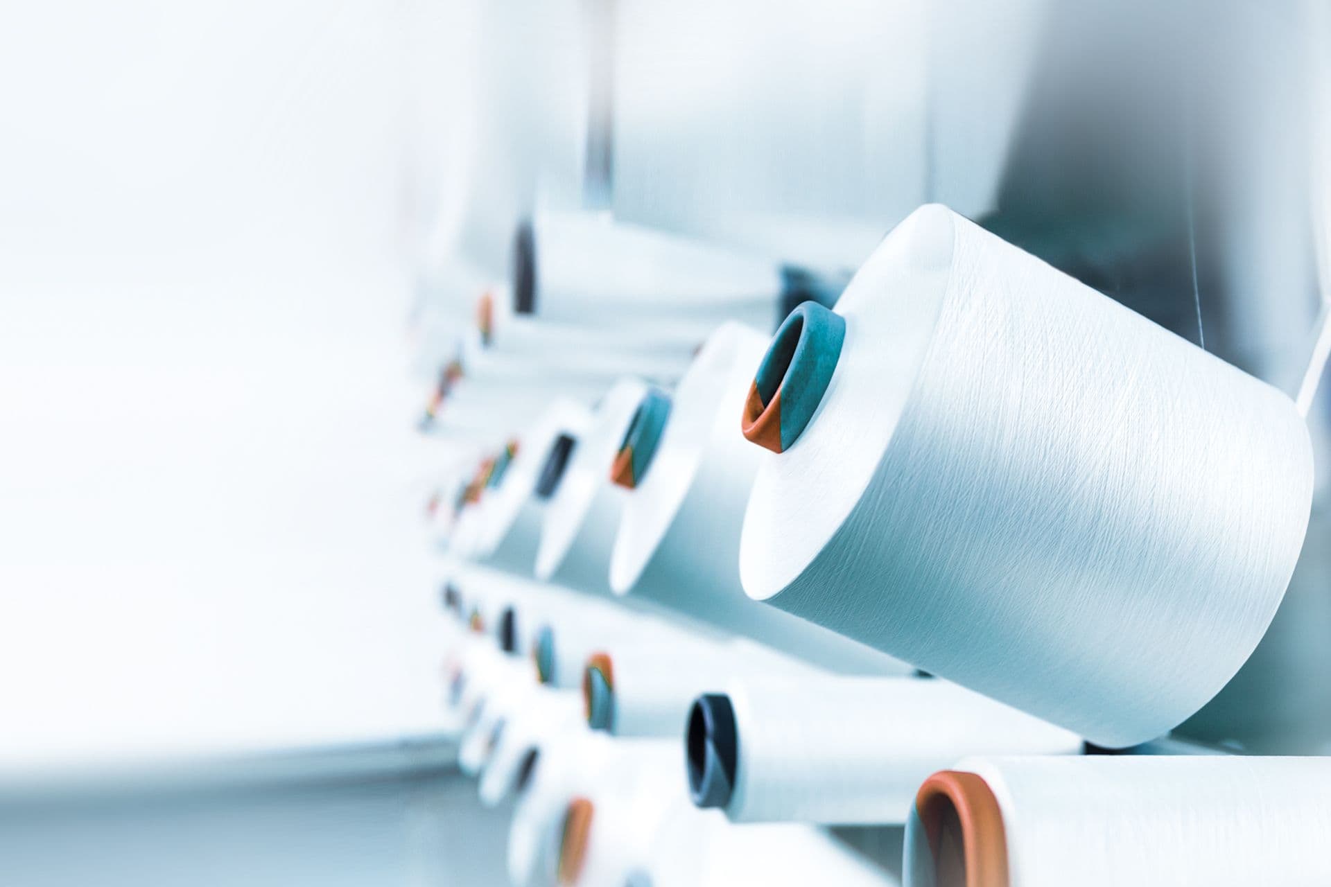 Mehrere Fadenspulen an einer Webmaschine.