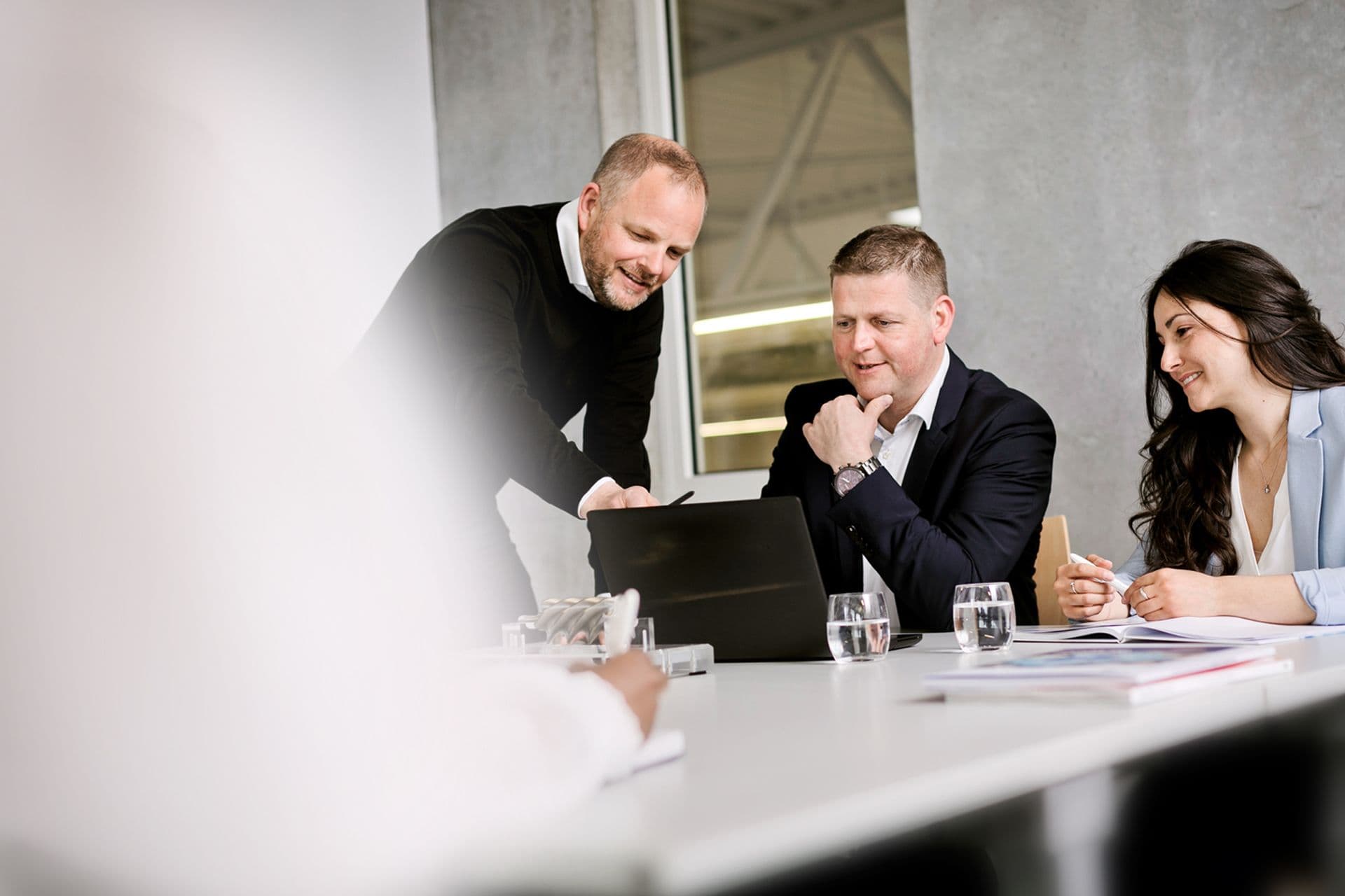 Drei BOGE Mitarbeiter sitzen in einem Konferenzraum und schauen gemeinsam auf einen Laptop