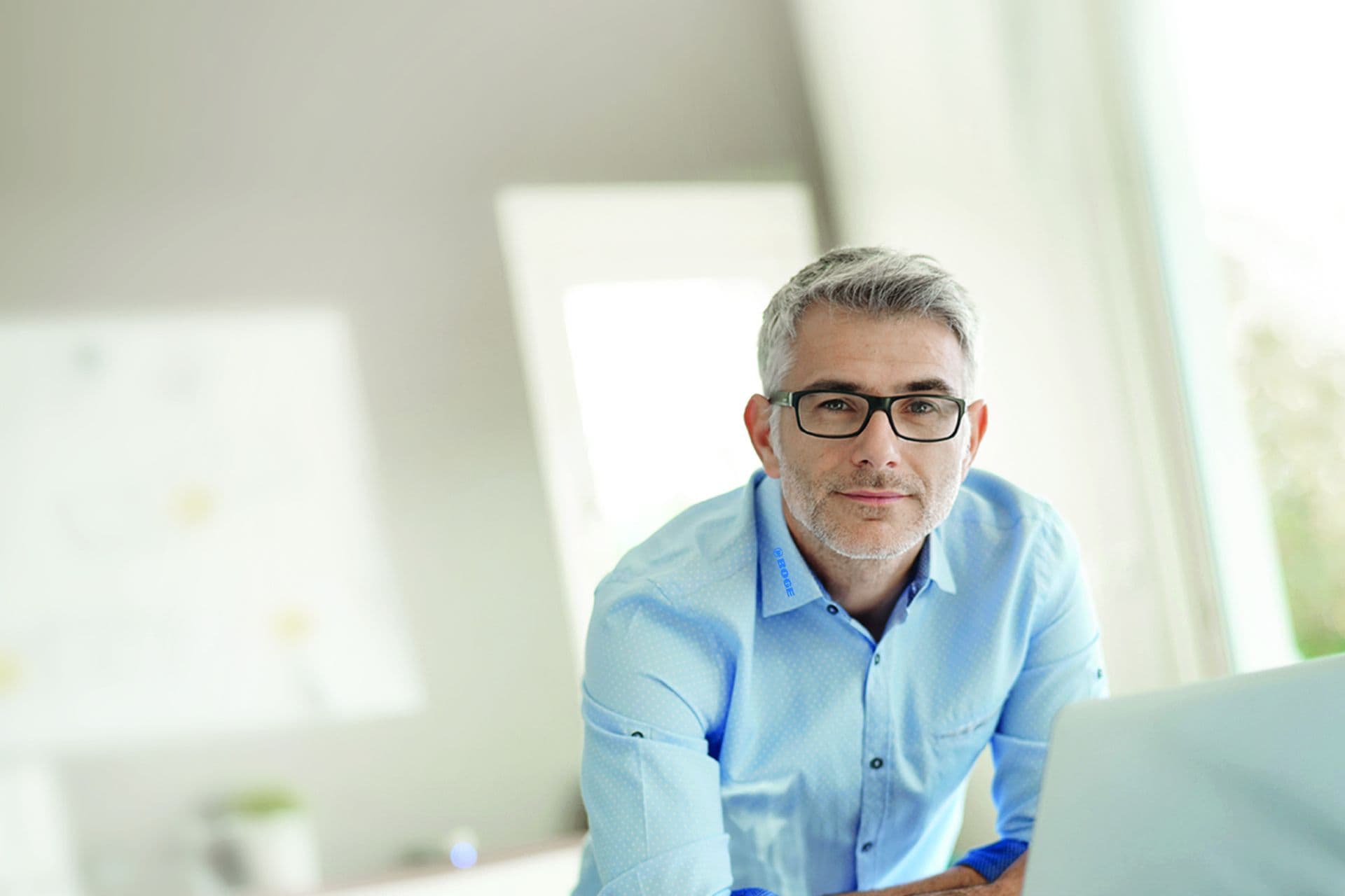 Mitarbeiter der an seinen schreibtischgelehnt in die Kamera guckt