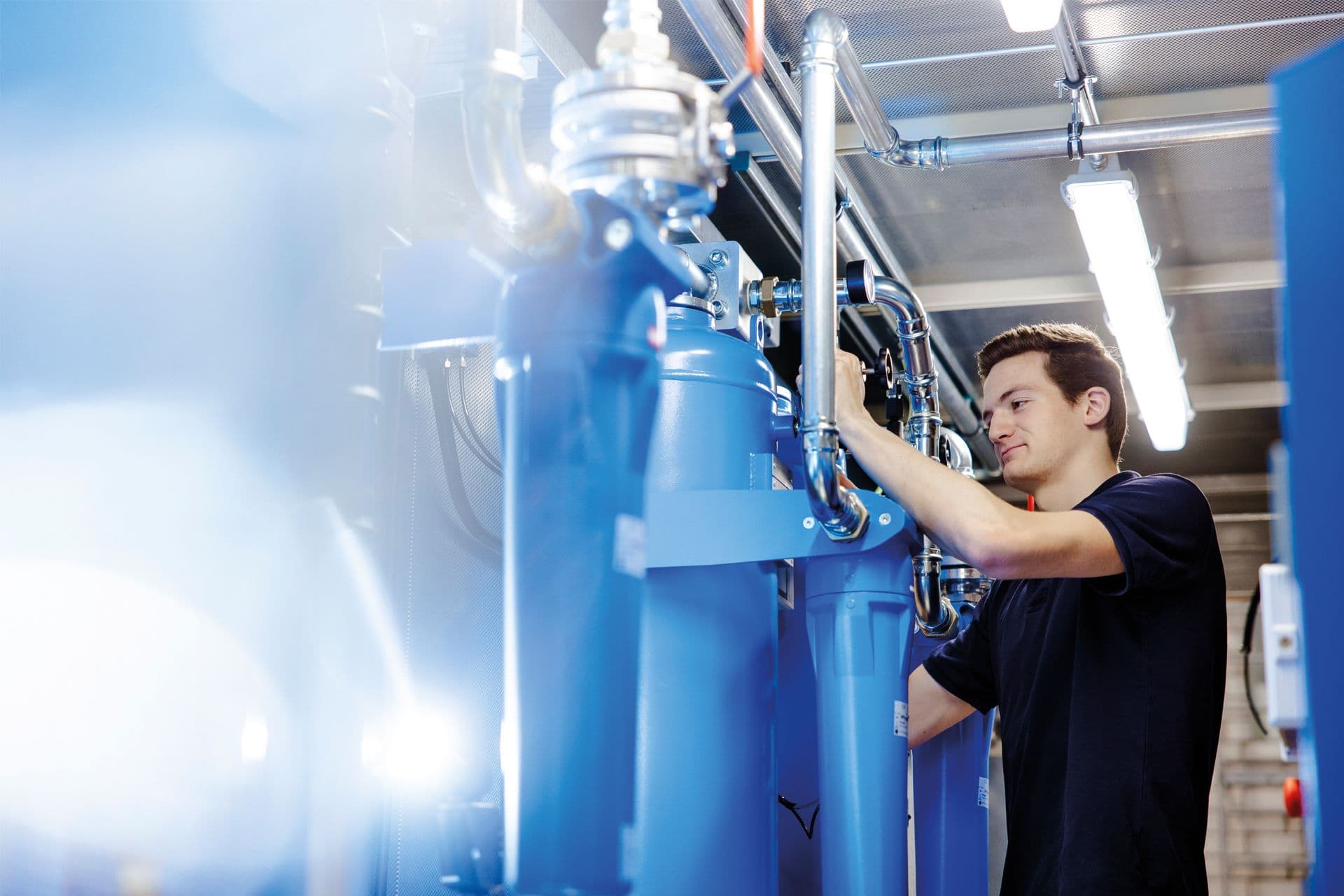 BOGE Servicetechniker arbeitet an einer Druckluftanlage innerhalb eines Containers an verschiedenen Rohren und Behaeltern