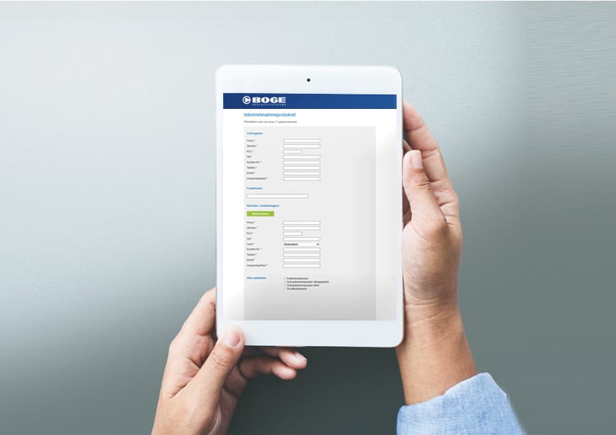 Hände halten ein Tablet mit BOGE Inbetriebnahmeprotokoll eines Kompressors
